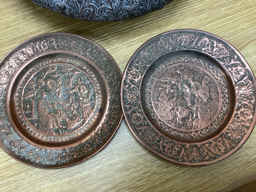 A large Eastern brass bowl cast with bands of seated deities, foliate scrolls and linear decoration and a pair of copper dishes